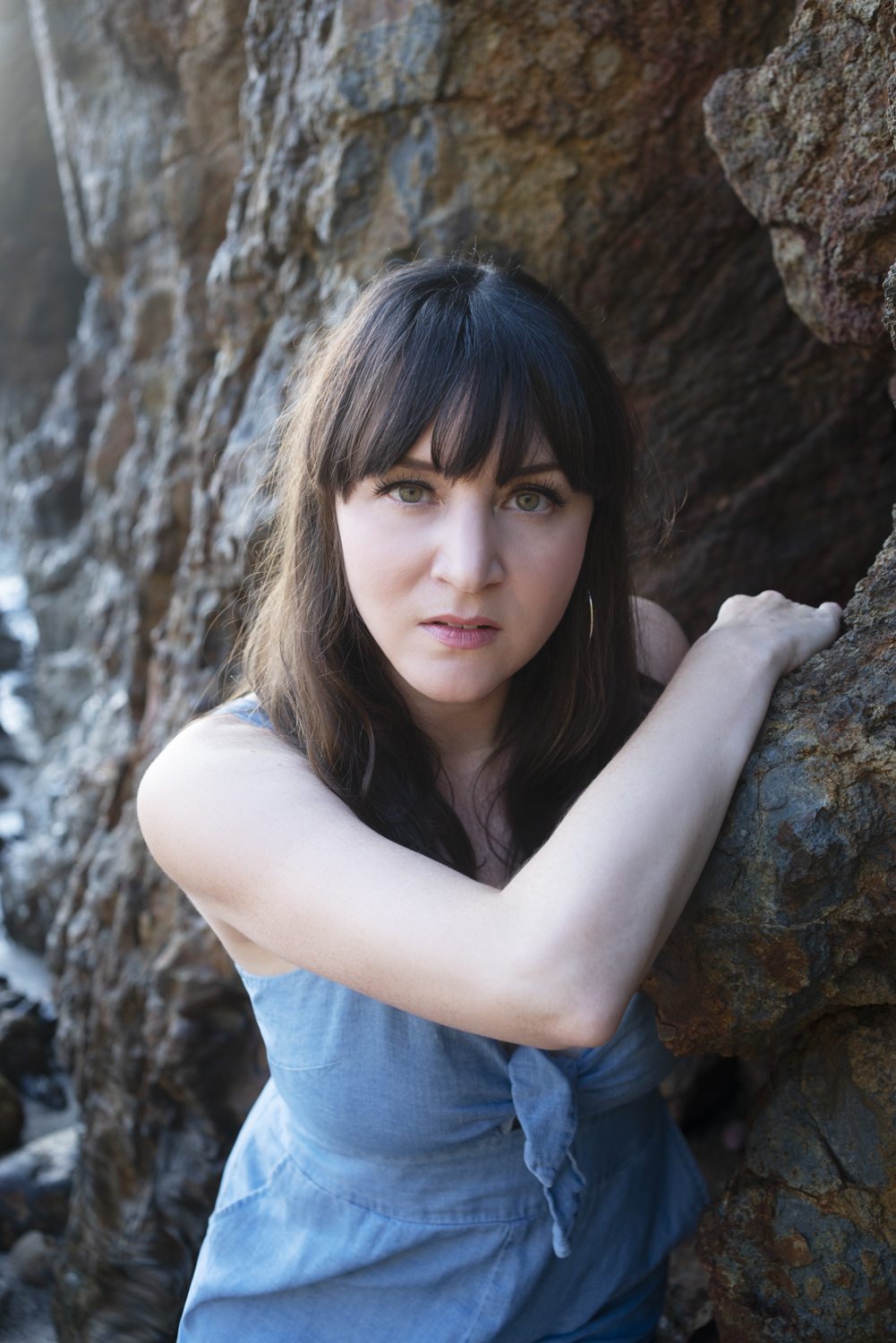 melissa smilow, a nutritional and energy healer, who is leaning against boulders by the ocean